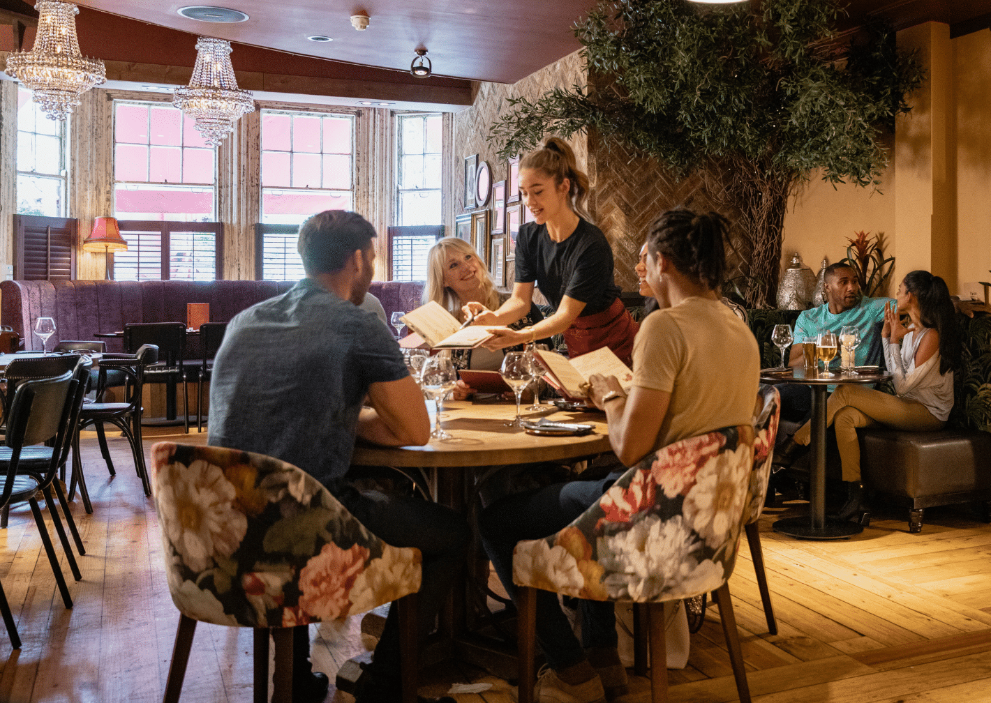table service restaurant Group of people dining in a table service restaurant as a waitress provides attentive service by handing menus to a table customers.