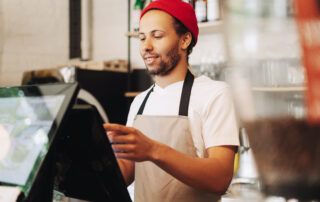 Barista taking an order taking order on digital pos system.